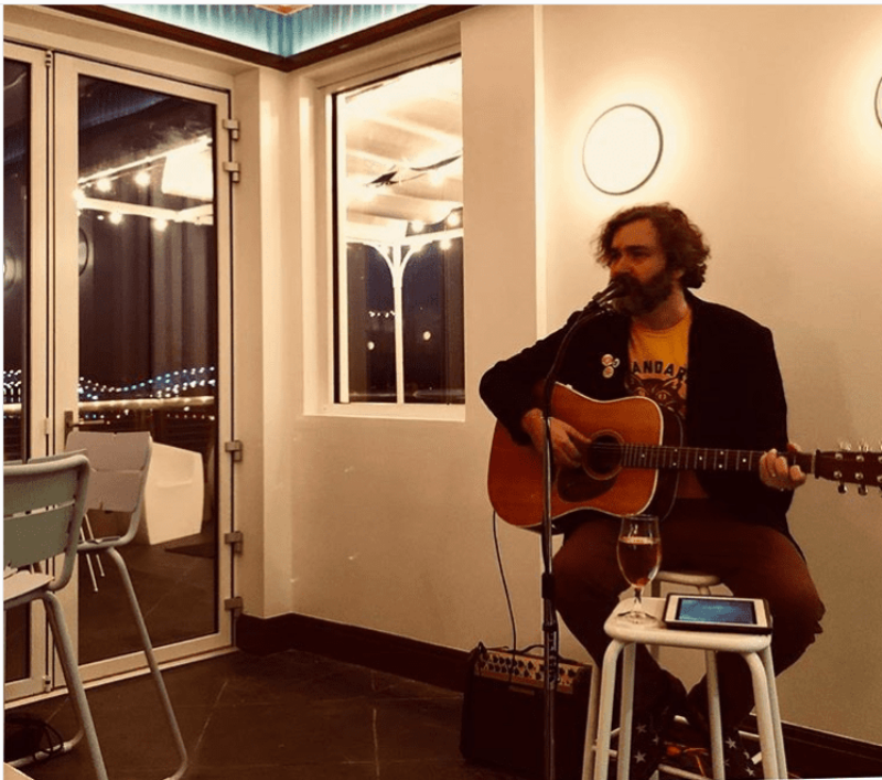 Bearded man singing with an acoustic guitar at our Memphis hotel