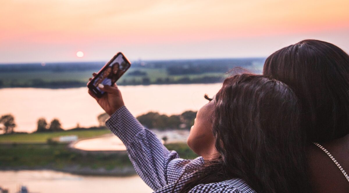 Two women taking a selfie with a sunset at our rooftop bar in Memphis